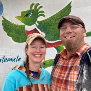 A man and woman standing in front of a painting.